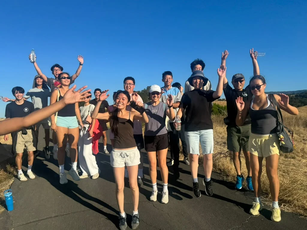 Students smiling and waving on an outdoor trail
